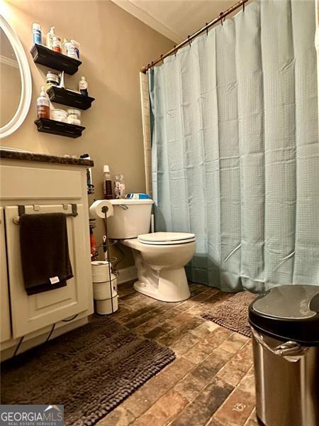 bathroom featuring ornamental molding, toilet, and a shower with curtain