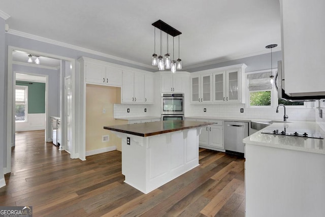 kitchen with dark hardwood / wood-style flooring, backsplash, stainless steel appliances, a center island, and white cabinetry