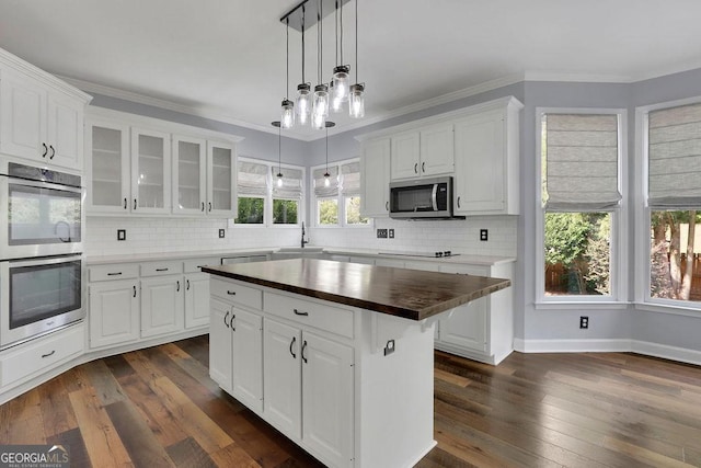 kitchen with wood counters, appliances with stainless steel finishes, dark wood-type flooring, white cabinets, and a center island