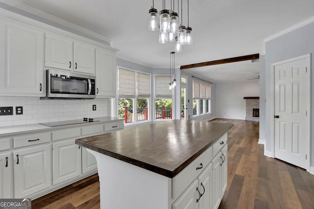 kitchen with wood counters, a fireplace, white cabinets, a kitchen island, and hanging light fixtures