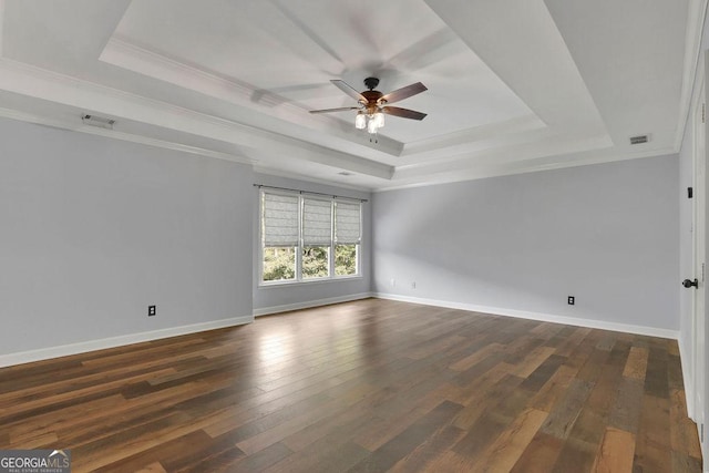 spare room featuring a tray ceiling, crown molding, and dark hardwood / wood-style floors