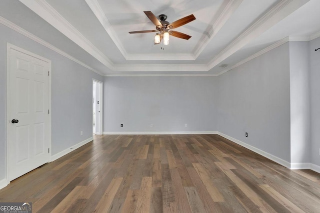 spare room featuring a raised ceiling, ceiling fan, dark wood-type flooring, and ornamental molding