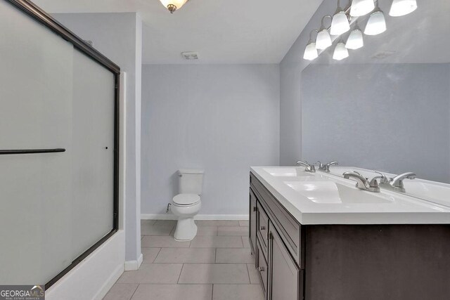 full bathroom with shower / bath combination with glass door, tile patterned flooring, vanity, and toilet