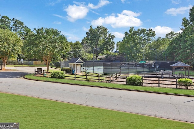 view of home's community with a lawn and tennis court