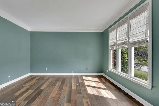 spare room featuring wood-type flooring and crown molding