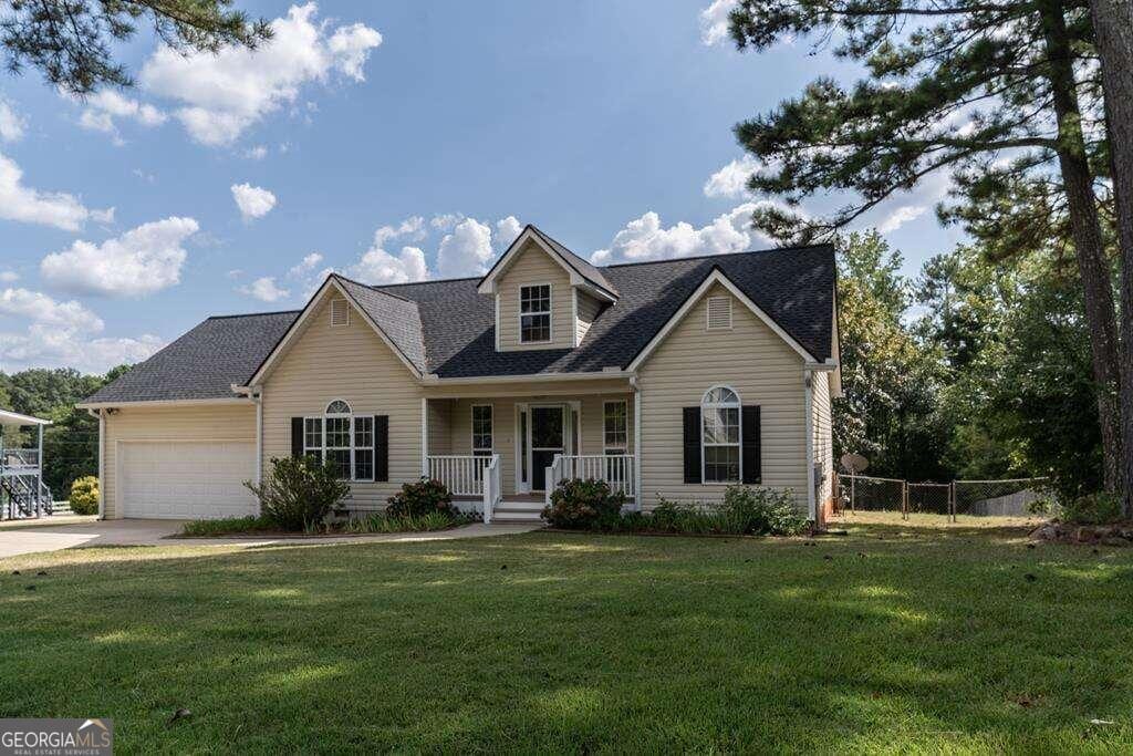 cape cod house with a front yard, concrete driveway, fence, an attached garage, and a porch