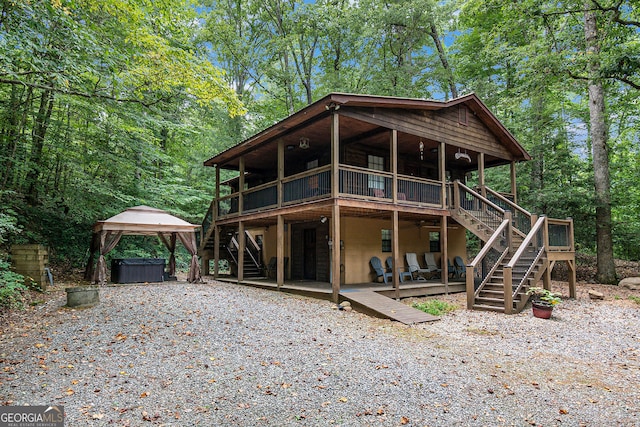 exterior space featuring a gazebo, a deck, stairway, and a hot tub