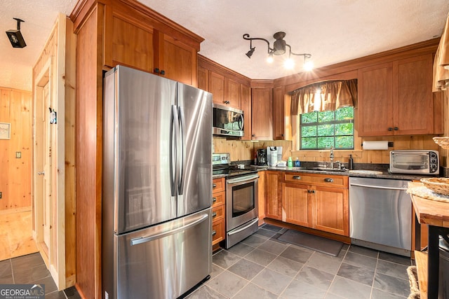 kitchen featuring a textured ceiling, sink, appliances with stainless steel finishes, and dark stone counters