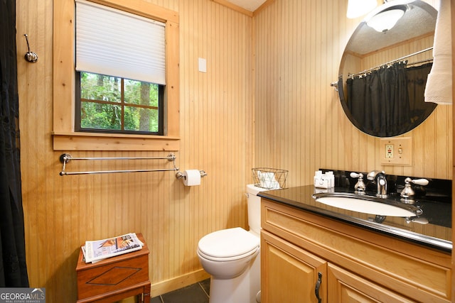 bathroom featuring tile patterned flooring, vanity, toilet, and wood walls