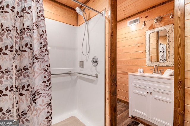 bathroom featuring visible vents, wood walls, a shower stall, vanity, and wood ceiling