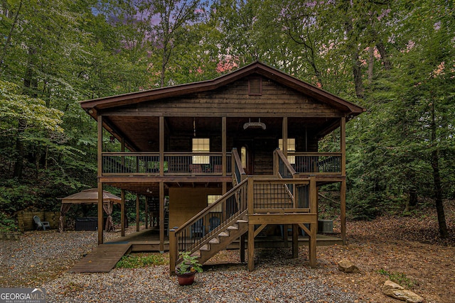 rustic home with a forest view, a gazebo, and stairway