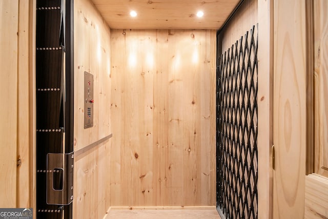 interior details with elevator, wood finished floors, recessed lighting, and wood walls