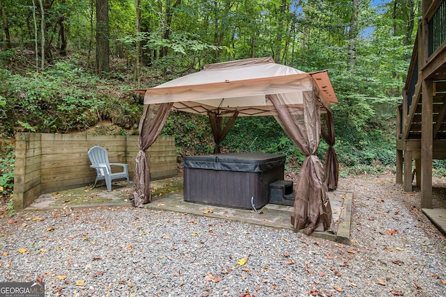 view of yard with a gazebo, a view of trees, a patio area, and a hot tub