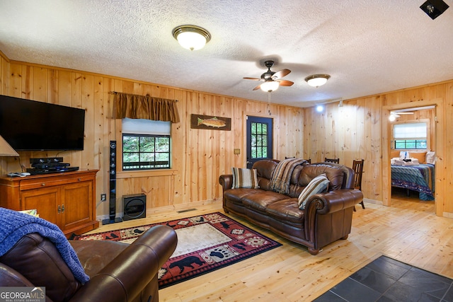 living room with a textured ceiling, plenty of natural light, ceiling fan, and light hardwood / wood-style floors