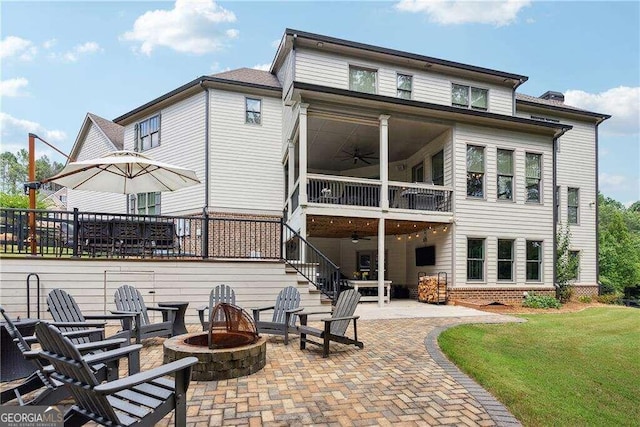 back of house featuring a balcony, a patio, ceiling fan, an outdoor fire pit, and a yard