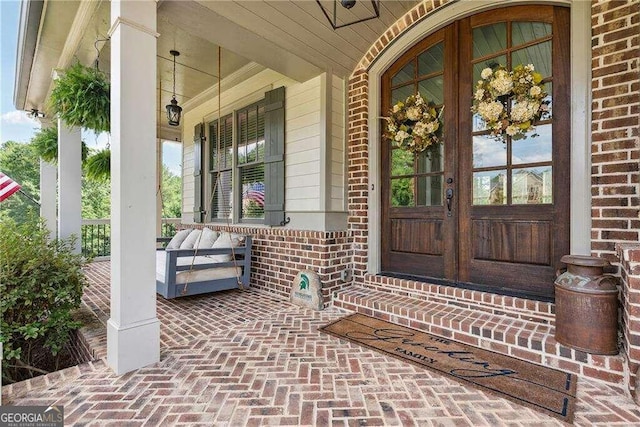 view of exterior entry featuring french doors and a porch