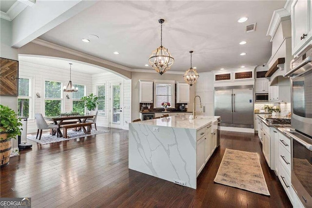 kitchen with pendant lighting, white cabinetry, an island with sink, and appliances with stainless steel finishes