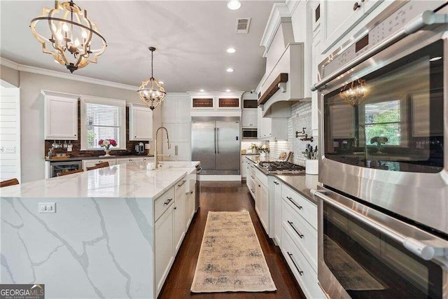 kitchen featuring decorative backsplash, white cabinetry, dark stone countertops, and decorative light fixtures