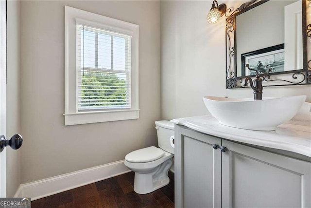 bathroom with wood-type flooring, vanity, toilet, and a healthy amount of sunlight