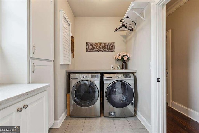 washroom with cabinets, washing machine and dryer, and light tile patterned floors