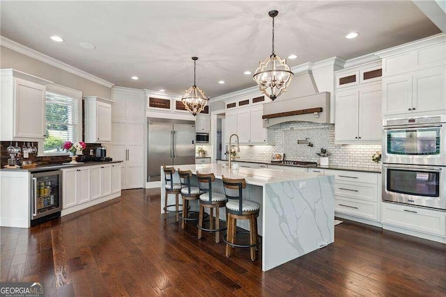 kitchen featuring built in appliances, dark hardwood / wood-style floors, beverage cooler, and an island with sink