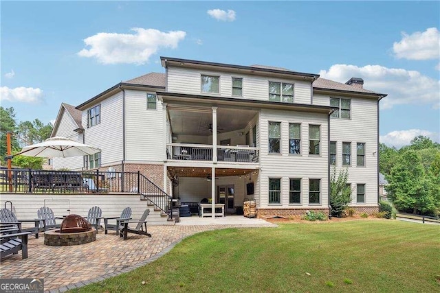 rear view of house with ceiling fan, a patio, an outdoor fire pit, and a lawn