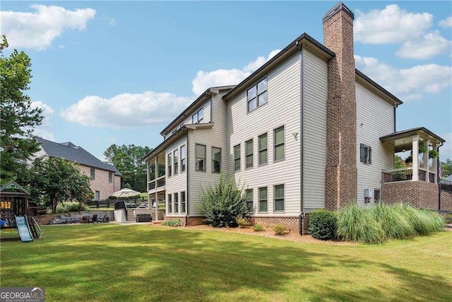 rear view of house featuring a playground and a yard