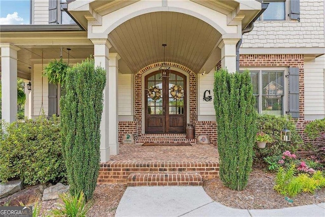 property entrance featuring covered porch and french doors