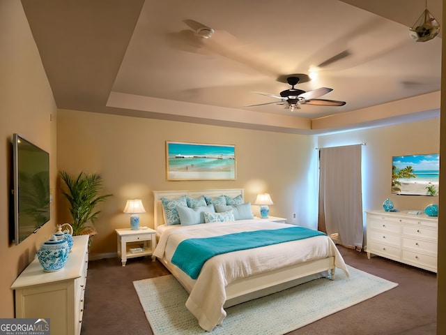 bedroom with a tray ceiling, baseboards, dark carpet, and ceiling fan