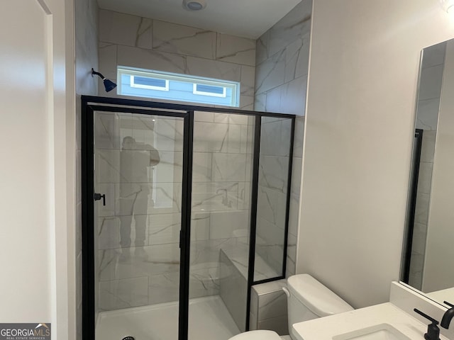 bathroom featuring a shower with door, vanity, and toilet