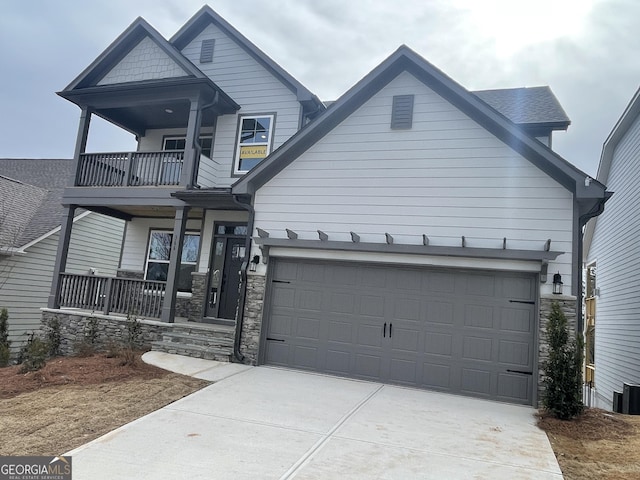 craftsman inspired home featuring a porch, a balcony, and a garage