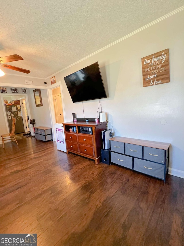 living room featuring ceiling fan, dark hardwood / wood-style flooring, a textured ceiling, and ornamental molding