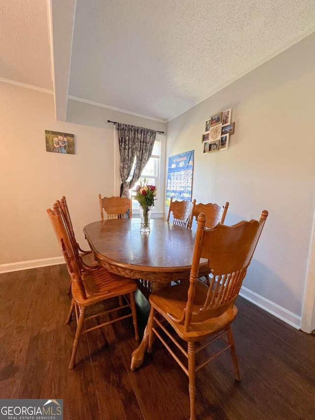 dining space with a textured ceiling, dark wood-type flooring, and beamed ceiling