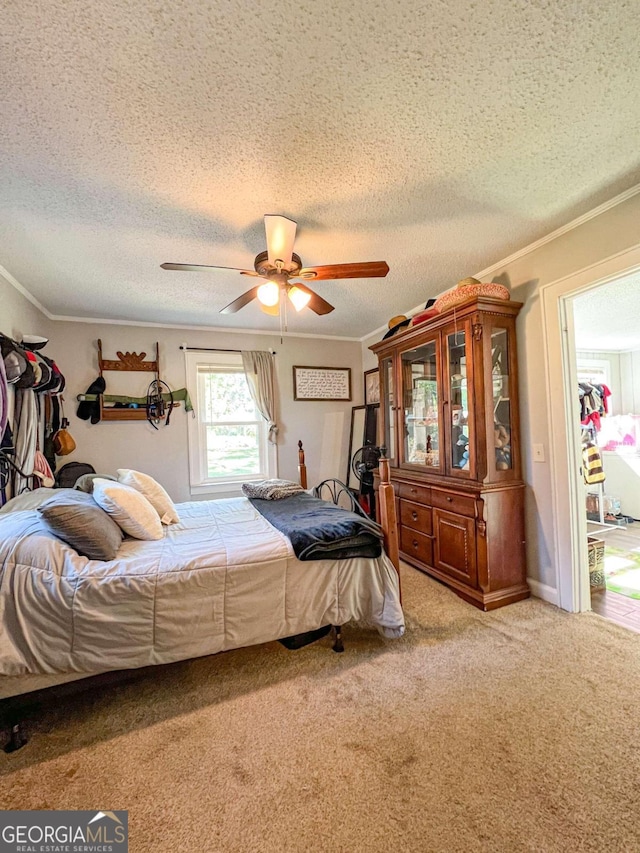 carpeted bedroom with a textured ceiling, ceiling fan, and crown molding