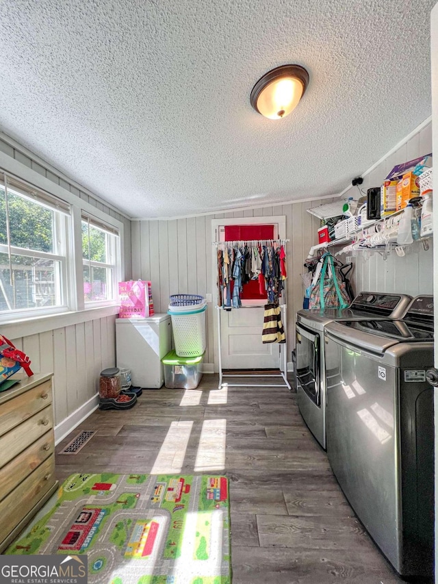 laundry room featuring hardwood / wood-style flooring, wood walls, separate washer and dryer, and a textured ceiling