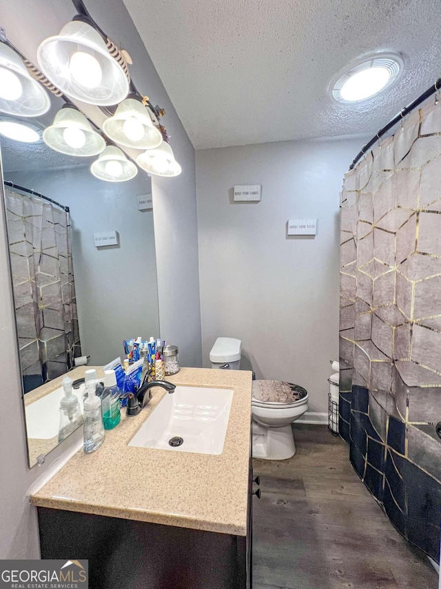 bathroom with wood-type flooring, a textured ceiling, toilet, vanity, and a shower with shower curtain