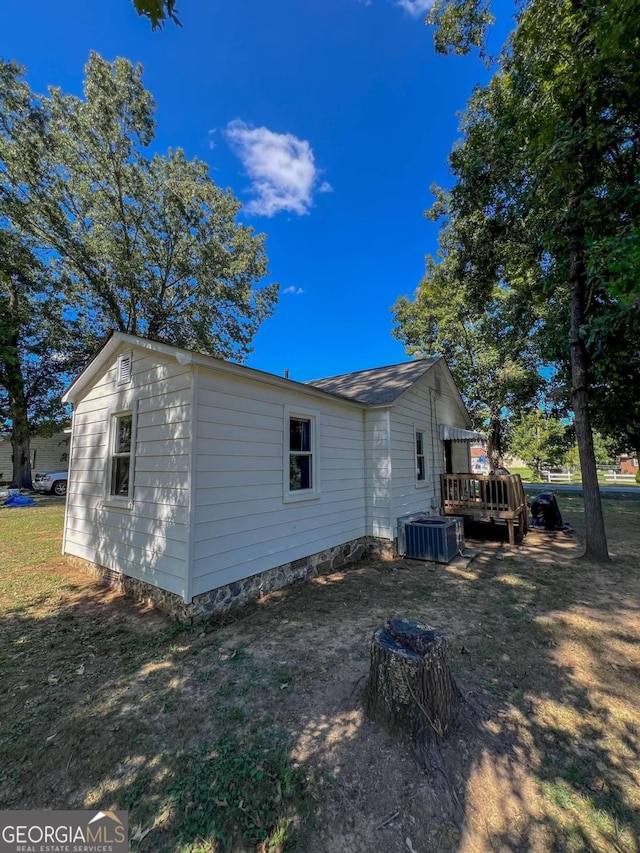 view of home's exterior with a wooden deck and central AC unit