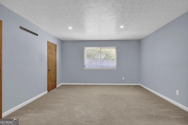 spare room featuring carpet, baseboards, and a textured ceiling