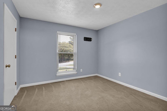 empty room featuring carpet floors, baseboards, and a textured ceiling
