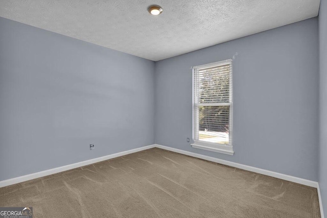 empty room with a textured ceiling, carpet flooring, and baseboards