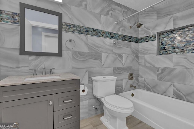 bathroom with toilet, tile walls, vanity, and shower / bathtub combination