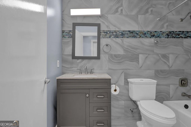 bathroom with vanity, bathtub / shower combination, tile walls, and toilet