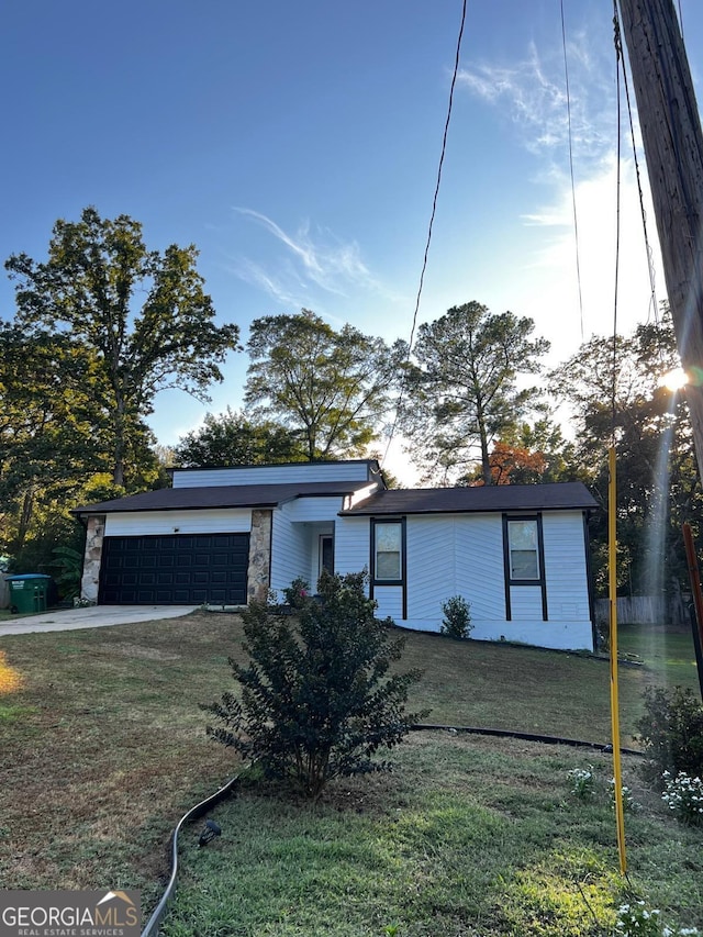 mid-century home with concrete driveway, a front yard, stone siding, and an attached garage