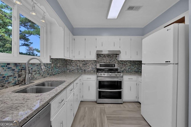 kitchen with visible vents, a sink, freestanding refrigerator, under cabinet range hood, and range with two ovens