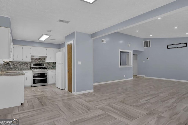 kitchen featuring white refrigerator, sink, white cabinets, and stainless steel gas range oven