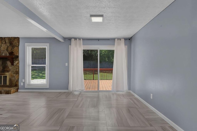 spare room with a fireplace, plenty of natural light, and a textured ceiling