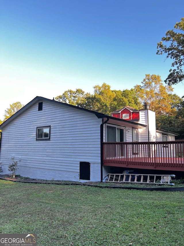 view of side of property with a deck and a lawn