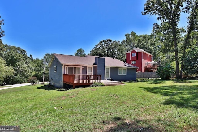 rear view of property featuring a wooden deck and a lawn