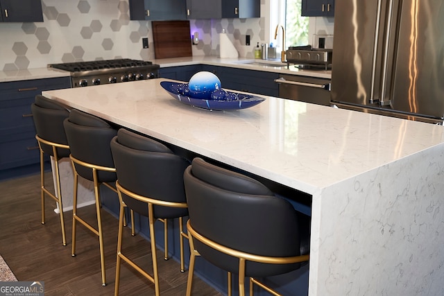 kitchen featuring dark wood-type flooring, stainless steel appliances, blue cabinets, and a breakfast bar