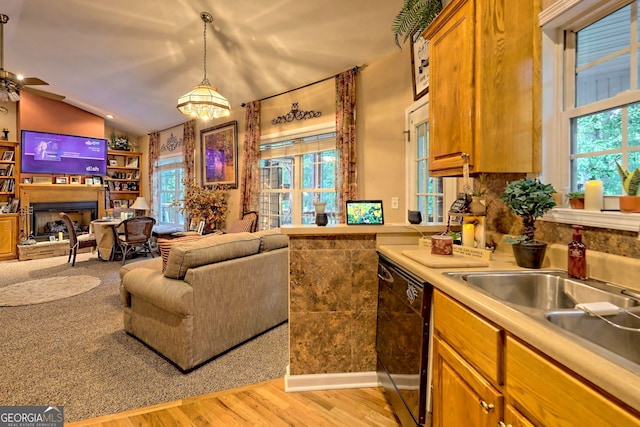 kitchen with pendant lighting, dishwasher, ceiling fan with notable chandelier, vaulted ceiling, and light hardwood / wood-style floors